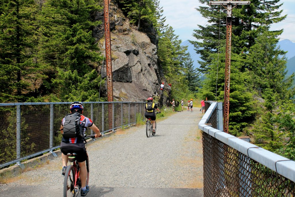 Cyclists and rock climbers on John Wayne Pioneer Trail in Cascades